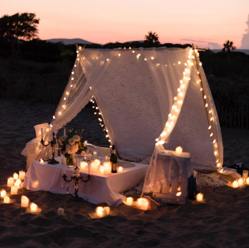 Escena acogedora en íntima en la playa a la luz de las velas